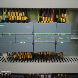TT Inwest - Panel sterowania Siemens Simatic S7-1200 z podłączonymi przewodami oznaczonymi żółtymi numerowanymi etykietami, widoczne diody sygnalizacyjne stanu pracy modułów.