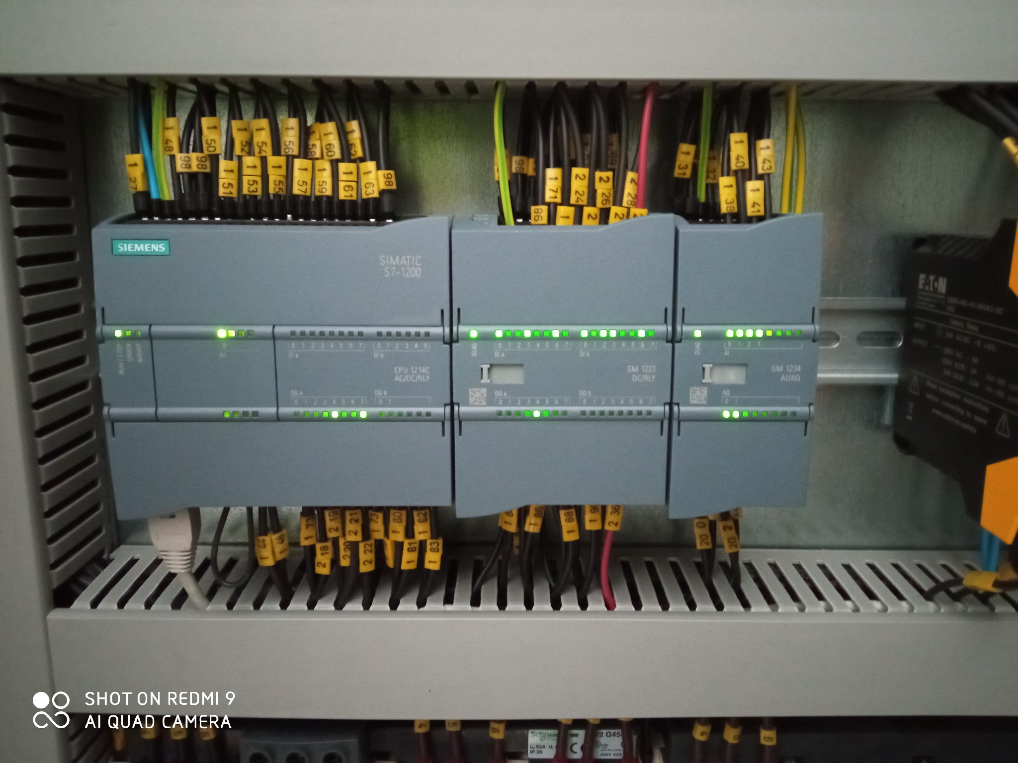 Panel sterowania Siemens Simatic S7-1200 z podłączonymi przewodami oznaczonymi żółtymi numerowanymi etykietami, widoczne diody sygnalizacyjne stanu pracy modułów.