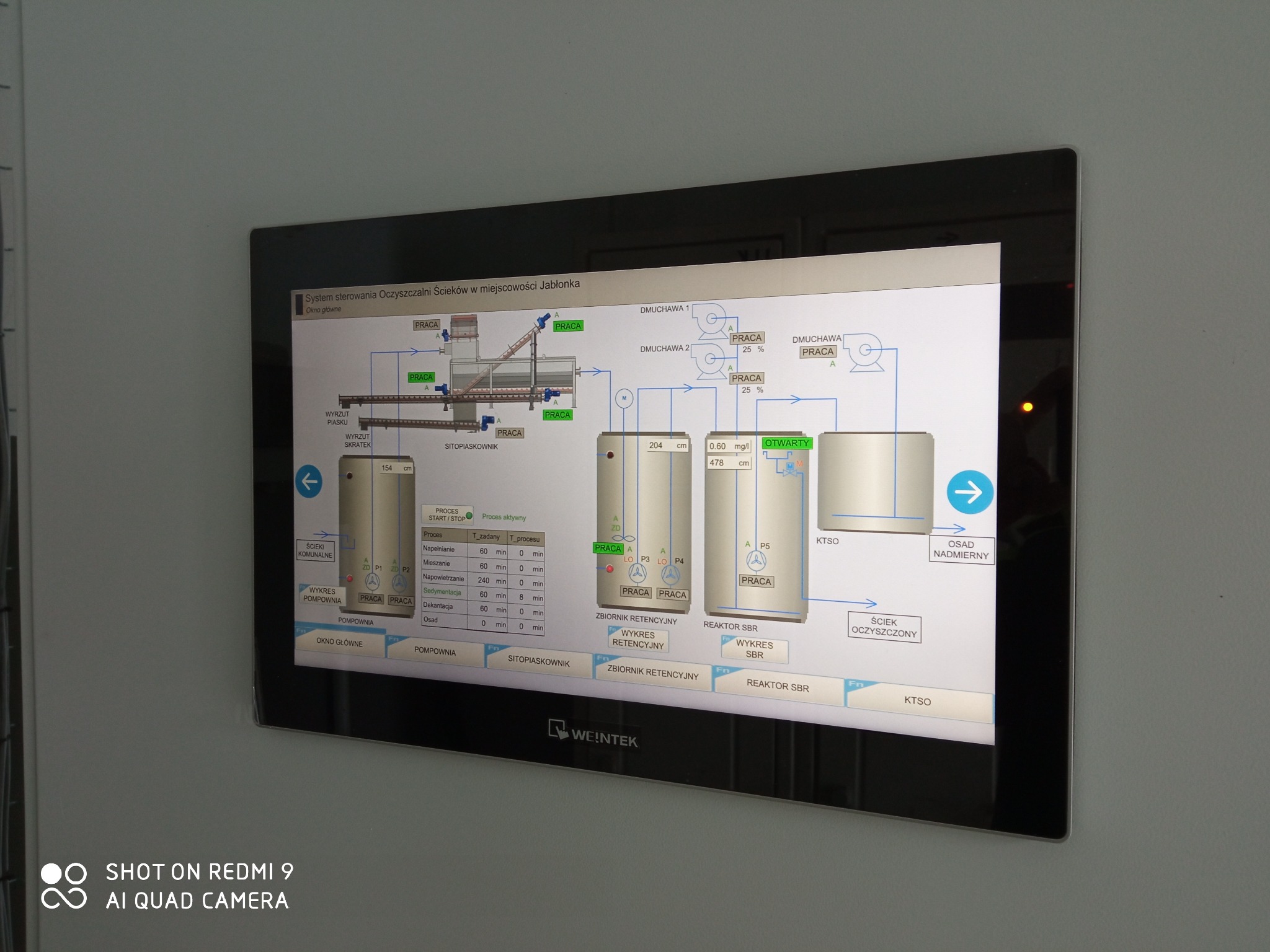 Ekran dotykowy HMI systemu sterowania procesami oczyszczalni ścieków z wizualizacją schematu technologicznego, wskazujący na aktualny status pracy poszczególnych elementów instalacji.