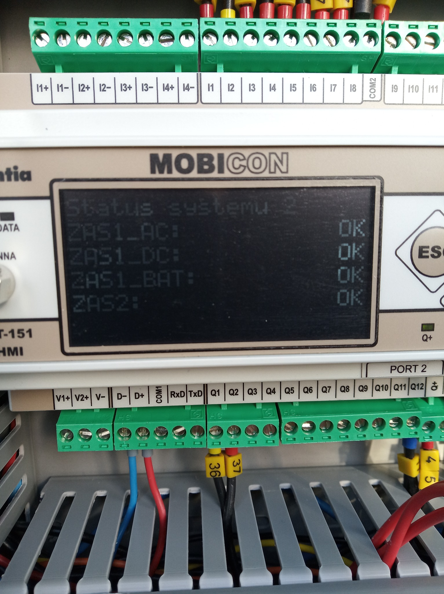 Ekran panelu sterowania Mobicon z wyświetlonym statusem systemu: ZAS1_AC, ZAS1_DC, ZAS1_BAT i ZAS2, wszystkie z oznaczeniem 'OK'. Widoczne zielone złącza z numerami i podłączonymi przewodami.