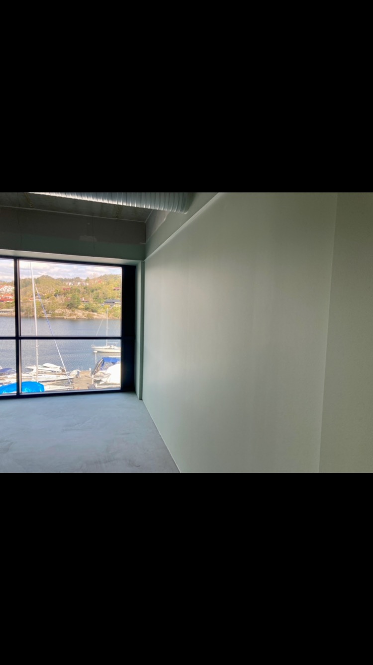 Świeżo pomalowane wnętrze biura z widokiem na przystań jachtową przez duże okno.