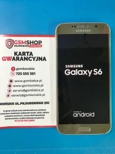 Smartfon Samsung Galaxy S6 leżący obok karty gwarancyjnej serwisu GSMshop, widoczne dane kontaktowe serwisu.