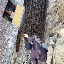 Natryskowe nakładanie hydroizolacji na nierównej ścianie, pozwala na najdokładniejsze zaizolowanie jej i skrócenie  czasu wykonywania usługi do minimum