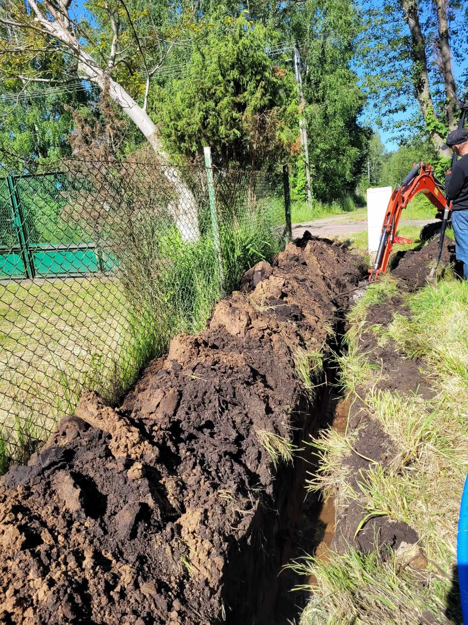 Wykopany rów w Radzyminie, prawdopodobnie pod kable elektryczne, z widocznym minikoparką Kubota i fragmentem niebieskiej rury.