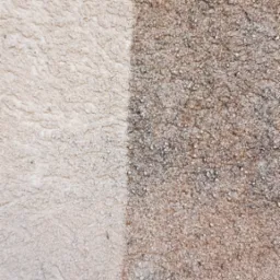 Fragment elewacji z wyraźnym podziałem na obszar czysty, jasny i obszar brudny, ciemniejszy, ukazujący efekt przed i po czyszczeniu.