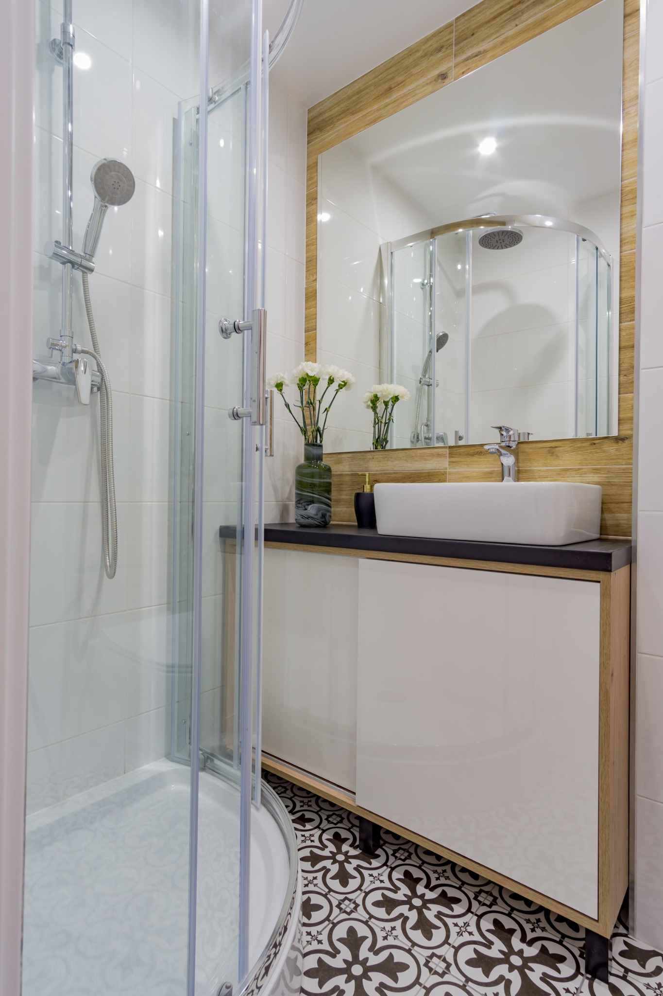 Nowoczesna łazienka z kabiną prysznicową, umywalką nablatową i dekoracyjnymi płytkami podłogowymi w stylu retro.