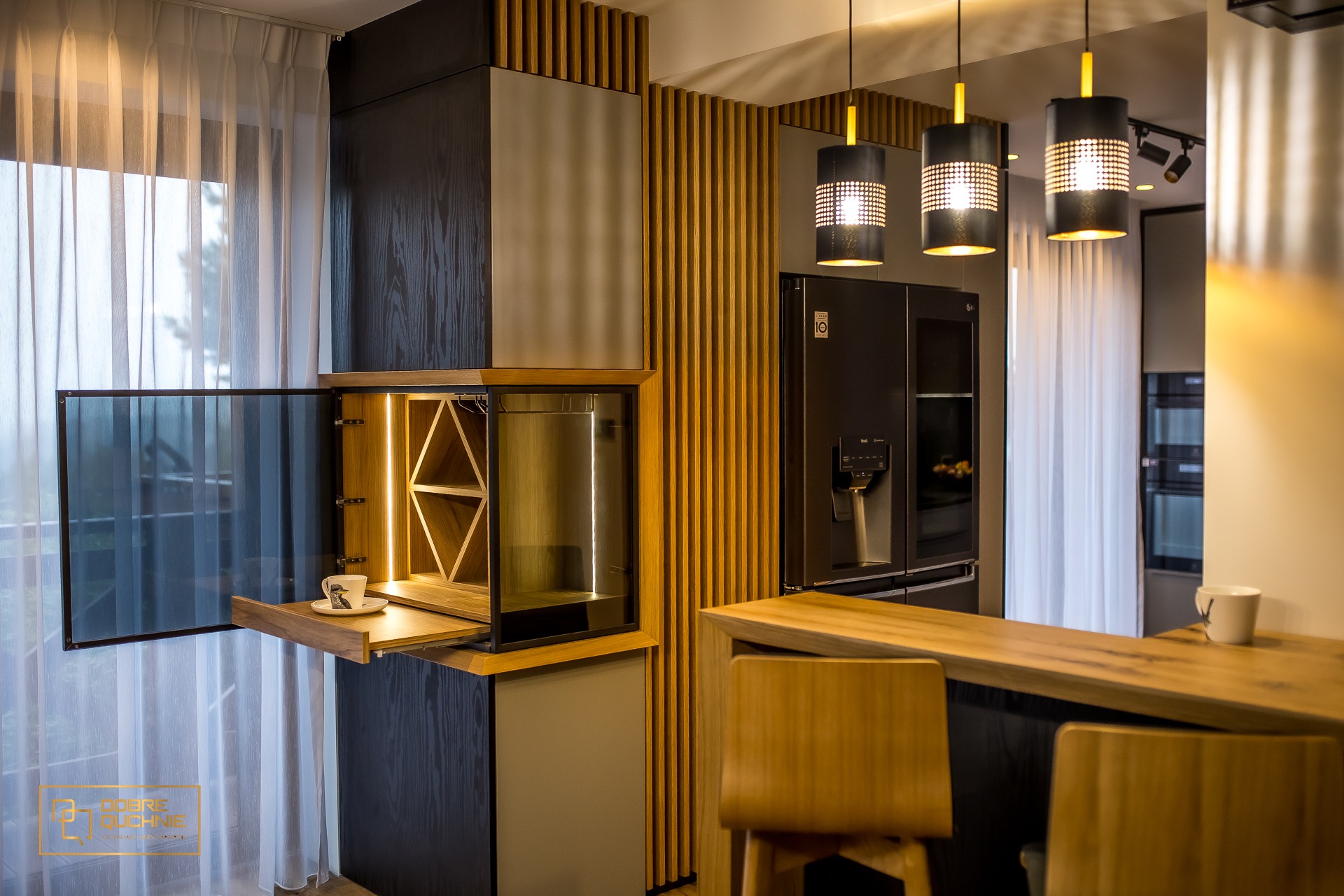 Nowoczesna kuchnia z czarnymi elementami, drewnianymi akcentami i oświetleniem LED, szafka z półkami na wino i wysuwanym blatem z filiżanką kawy, widok na okno z białymi zasłonami.