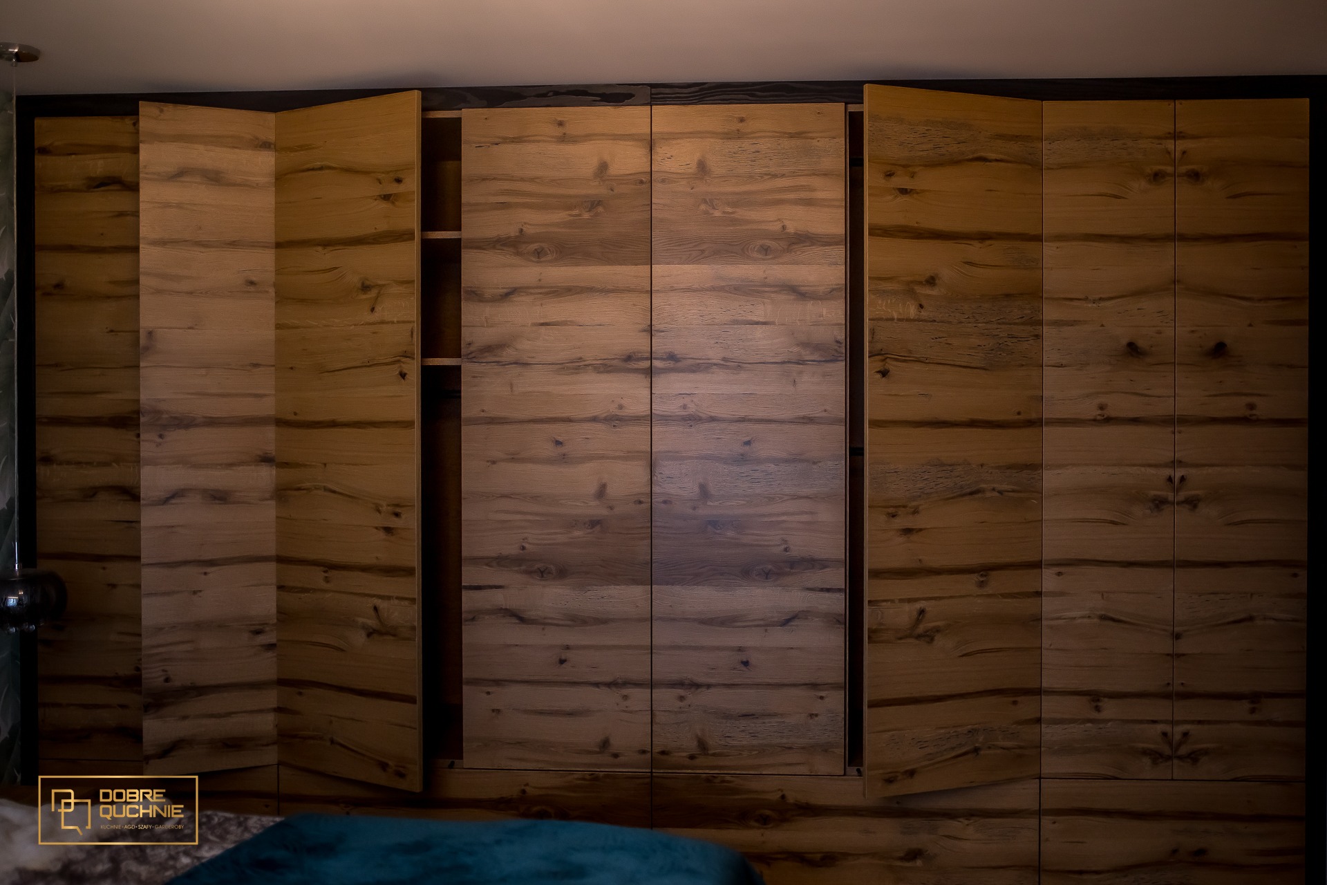 Duża szafa z drewnianymi frontami, część drzwi otwartych, ukazujących półki wewnątrz, widoczne słoje drewna.