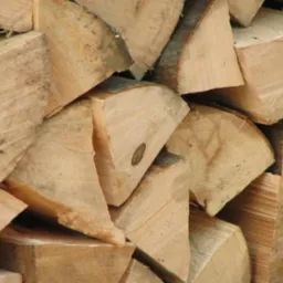 Ułożone, pocięte kawałki drewna z widocznymi słojami i korą, przygotowane do spalenia.