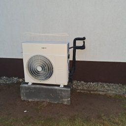 ARKOS - INSTAL ARKADIUSZ STENKA - Zamontowana zewnętrzna jednostka pompy ciepła Viessmann na betonowym fundamencie przy ścianie budynku z widocznymi rurami izolowanymi termicznie.