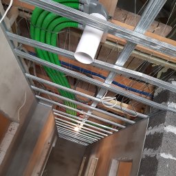 ARKOS - INSTAL ARKADIUSZ STENKA - Montaż instalacji wentylacyjnej z użyciem zielonych, elastycznych rur w budynku w stanie surowym w Luzinie, widok z dołu na konstrukcję podwieszanego sufitu.