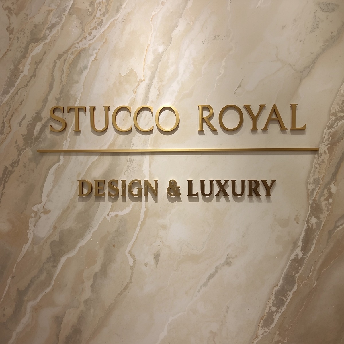 Ściana z efektem marmuru, z napisem 'STUCCO ROYAL DESIGN & LUXURY' w złotych literach, podkreślającym luksusowe wykończenie wnętrza.