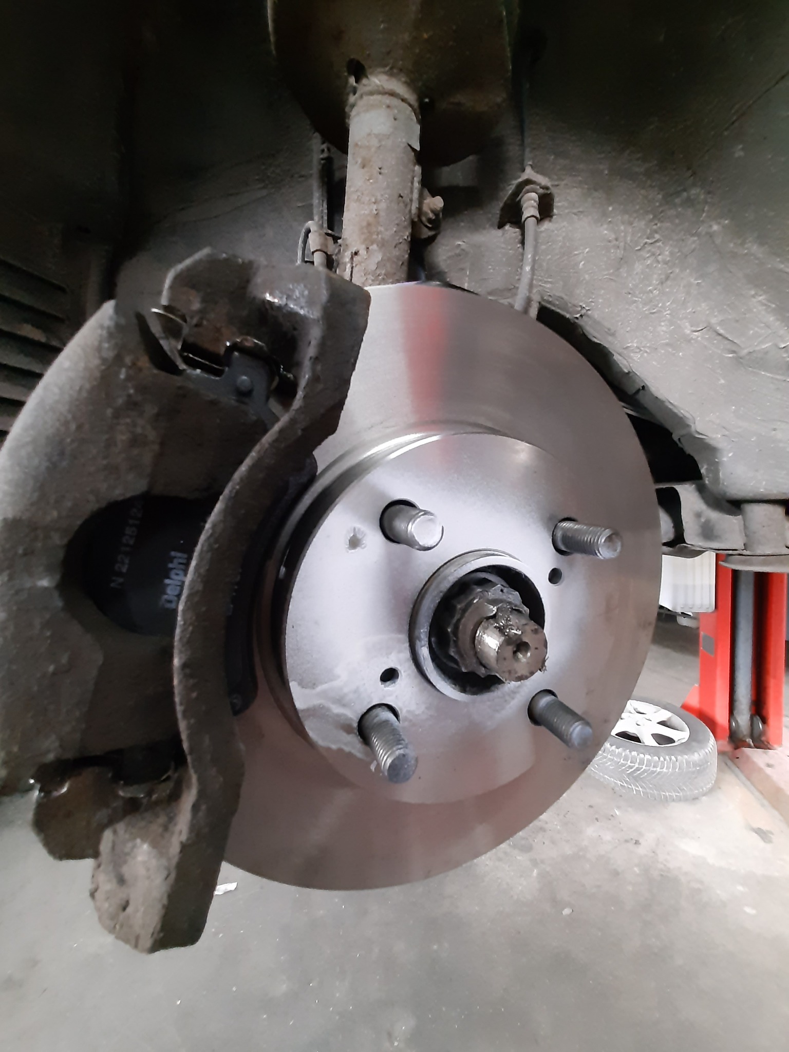 Nowa tarcza hamulcowa zamontowana w samochodzie w warsztacie w Klaudynie, widoczne elementy zawieszenia i zacisk hamulcowy.