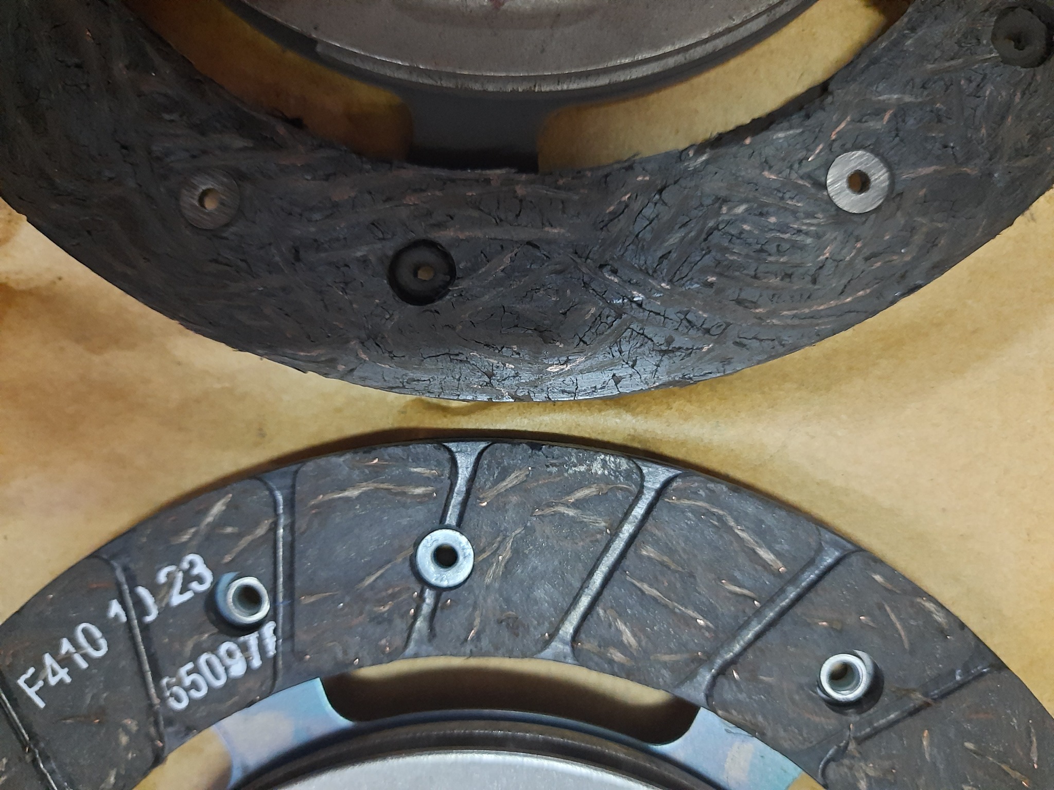 Zużyte tarcze sprzęgłowe z widocznymi śladami eksploatacji, zarysowaniami i numerami seryjnymi F410 10 23 i 65097F.
