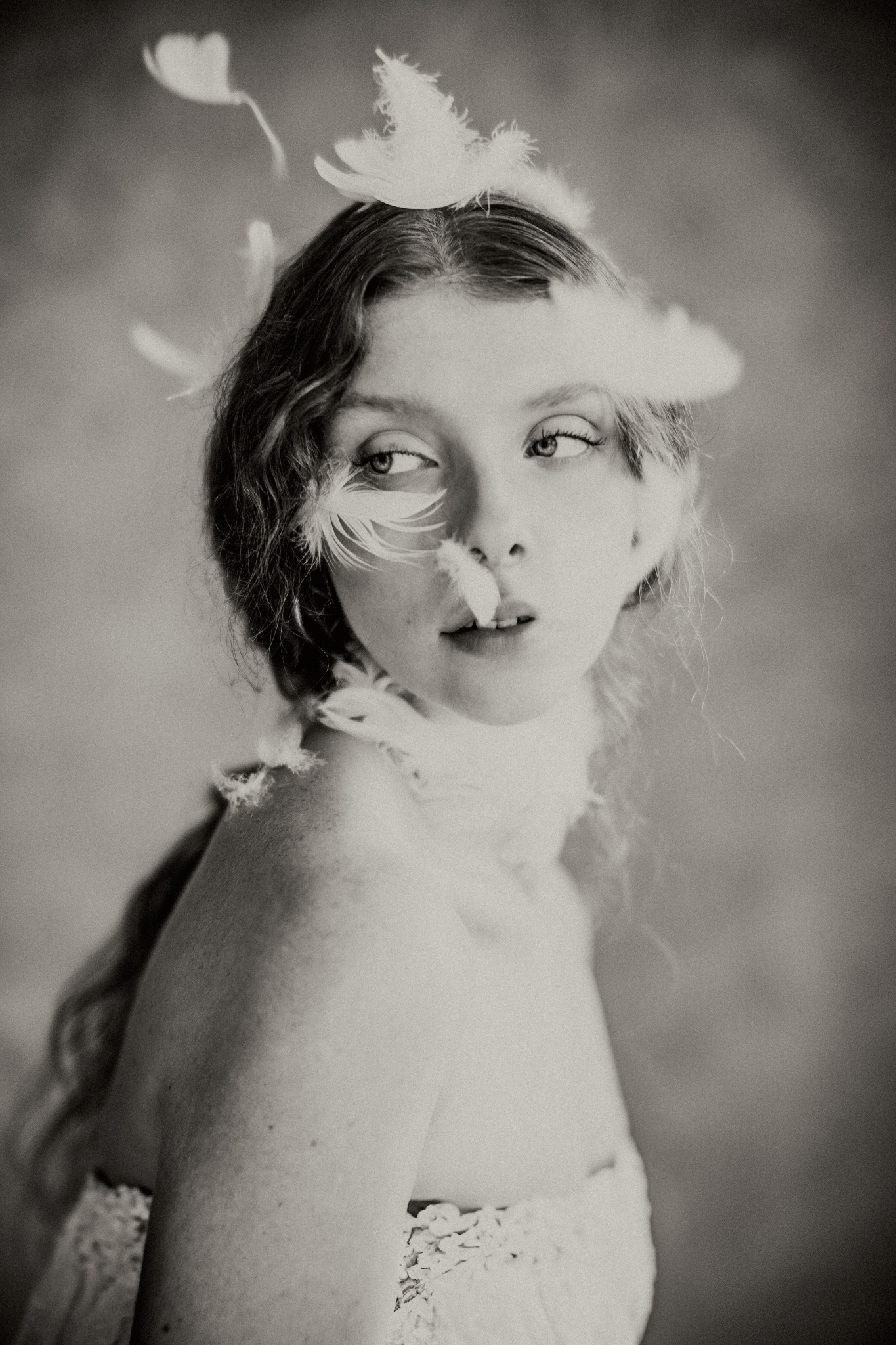 Portret kobiety w stylu vintage z piórami, spoglądającej w bok, w delikatnej bieliźnie z koronkowym wykończeniem.