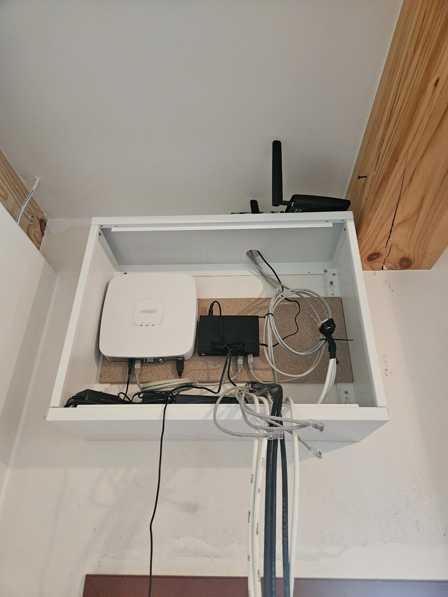 Wewnętrzna szafka z zamontowanym punktem dostępowym WiFi marki Dahua, routerem i okablowaniem sieciowym, widok od dołu.