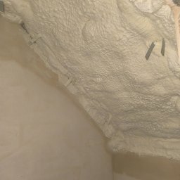 Hubert Gurzyński PUR-DOM - Ściana i strop po natrysku pianki izolacyjnej. Widoczne metalowe elementy mocujące. Szorstka faktura piany. Izolacja poddasza.