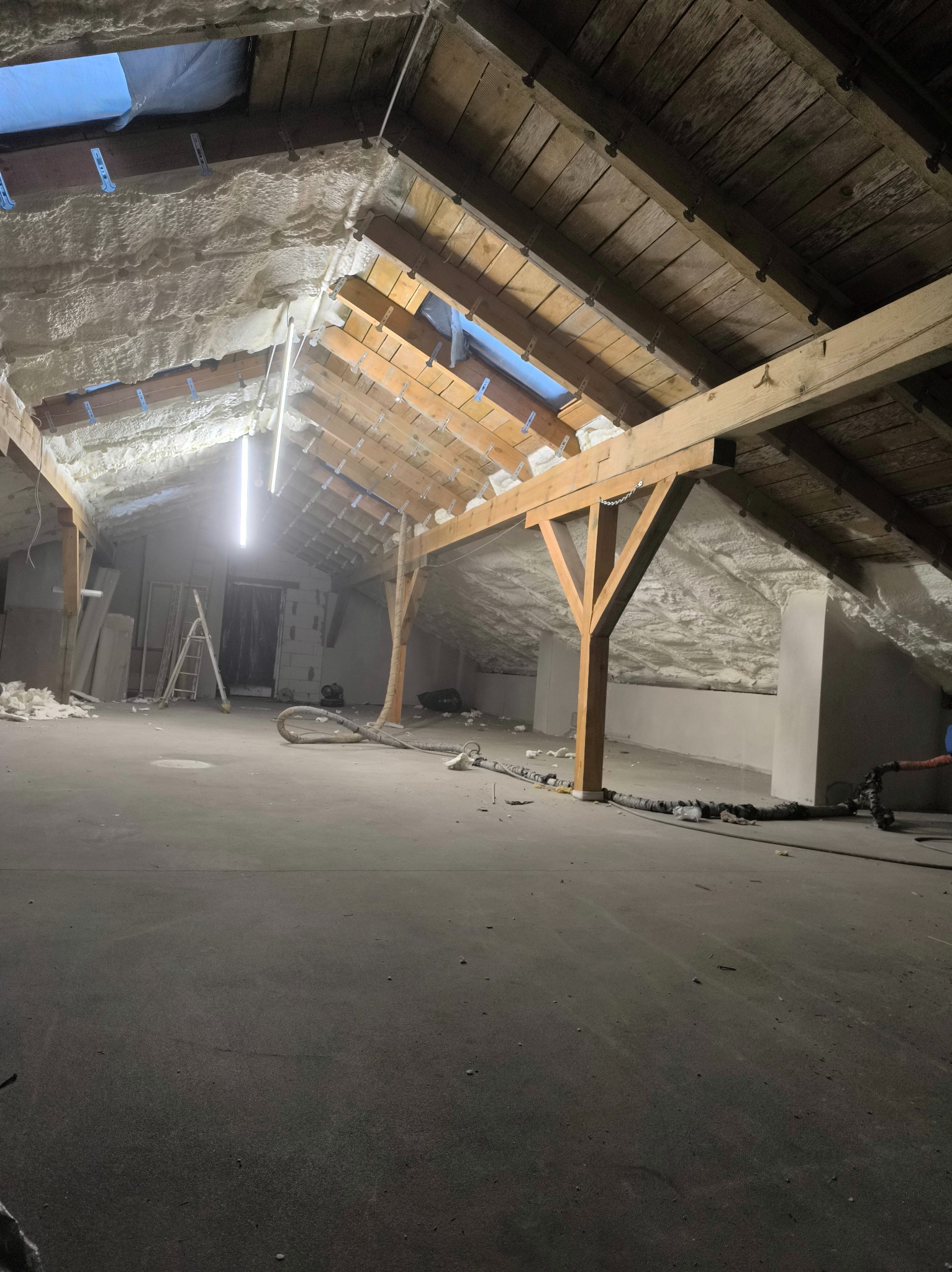 Ocieplone poddasze pianką w Iłowo-Osadzie. Widoczne drewniane elementy konstrukcyjne i równomierna warstwa izolacji natryskowej na skośnych powierzchniach.