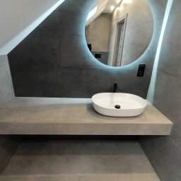 Tomek - Nowoczesna łazienka na poddaszu z szarą, kamienną umywalką nablatową, okrągłym lustrem z podświetleniem LED i czarną armaturą.