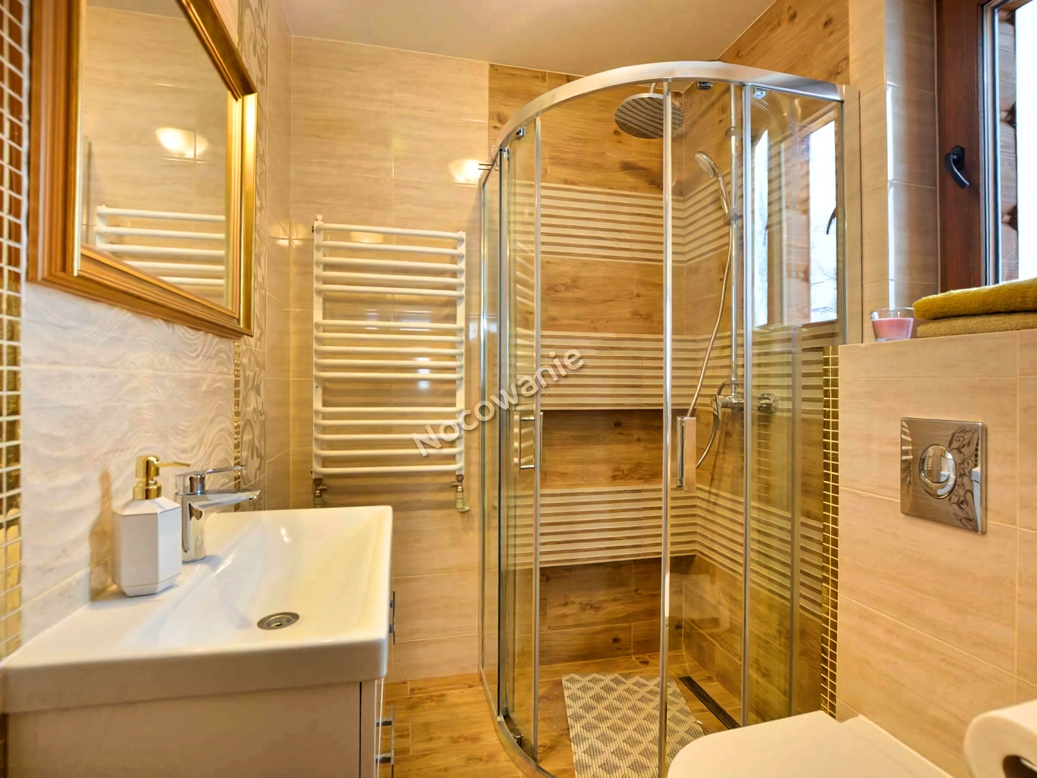 Nowoczesna łazienka z kabiną prysznicową typu walk-in, umywalką nablatową z dozownikiem mydła w geometrycznym kształcie i grzejnikiem drabinkowym.