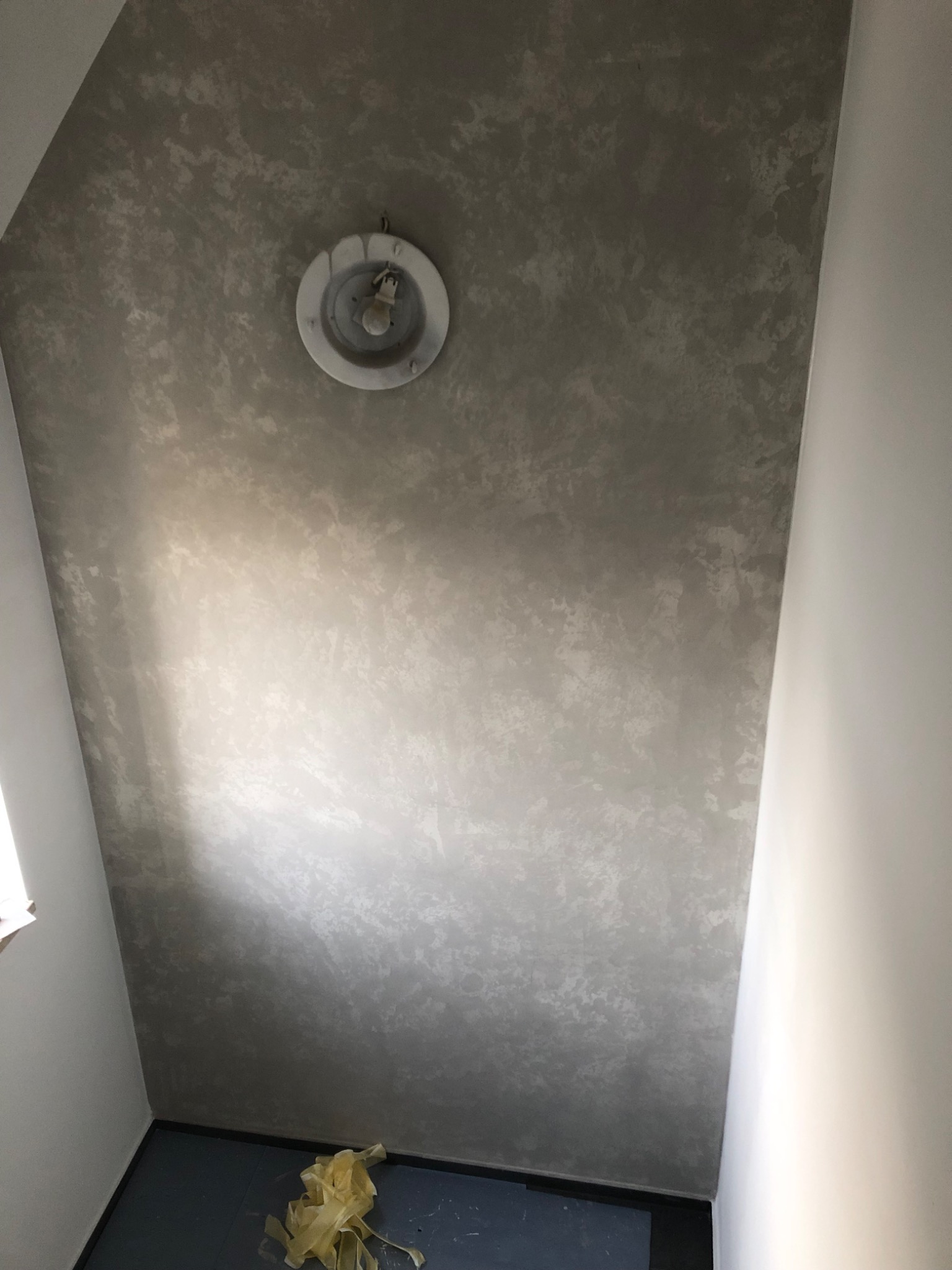 Dekoracyjna, szara struktura na suficie w Drzewicy, widoczna oprawa oświetleniowa i fragment podłogi z resztkami folii malarskiej.