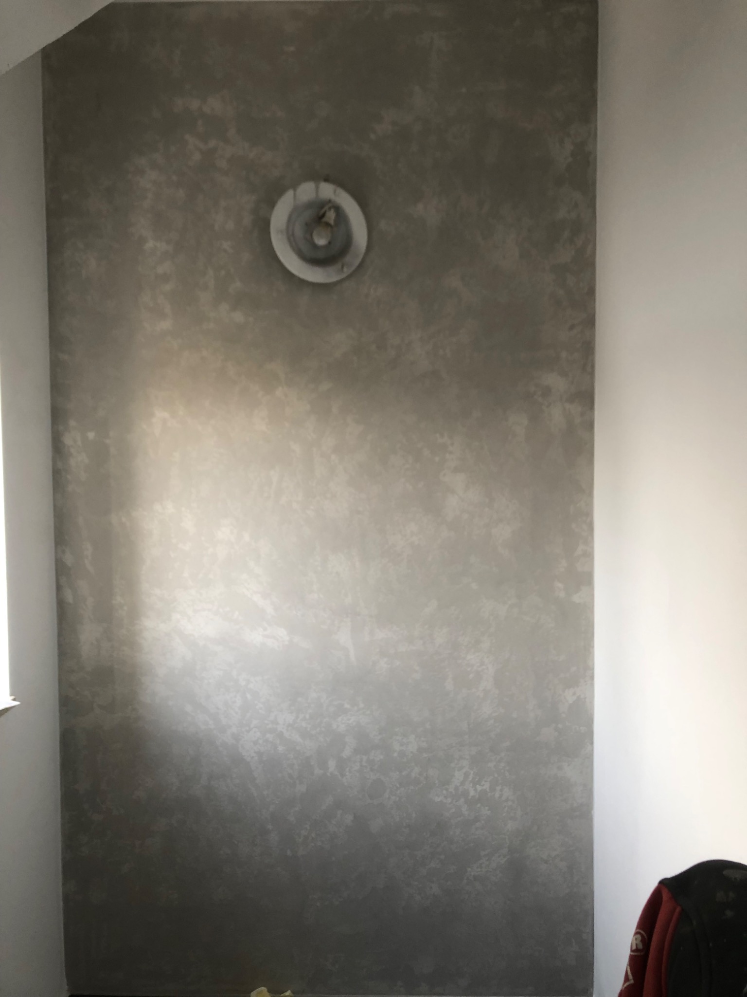 Ściana po szpachlowaniu i malowaniu dekoracyjnym, z widoczną fakturą i zamontowaną puszką elektryczną pod oświetlenie. Kolorystyka szaro-srebrna z efektem cieniowania.