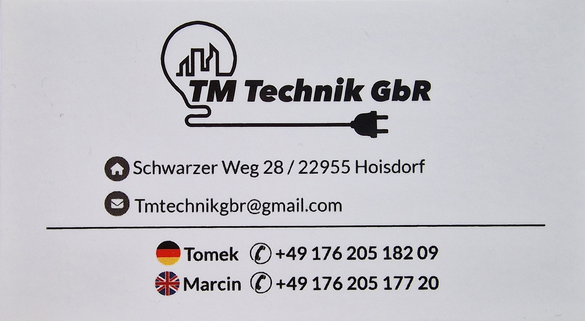 Wizytówka firmy TM Technik GbR z logotypem żarówki zarysowanej budynkami, adresem, adresem email oraz danymi kontaktowymi do Tomka i Marcina.
