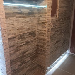 Jagi Kacper Jaglarz - Ściana wyłożona dekoracyjnym kamieniem elewacyjnym w odcieniach beżu i brązu, z podświetloną wnęką LED i ukrytym otworem rewizyjnym, ukazująca efekt po remoncie.