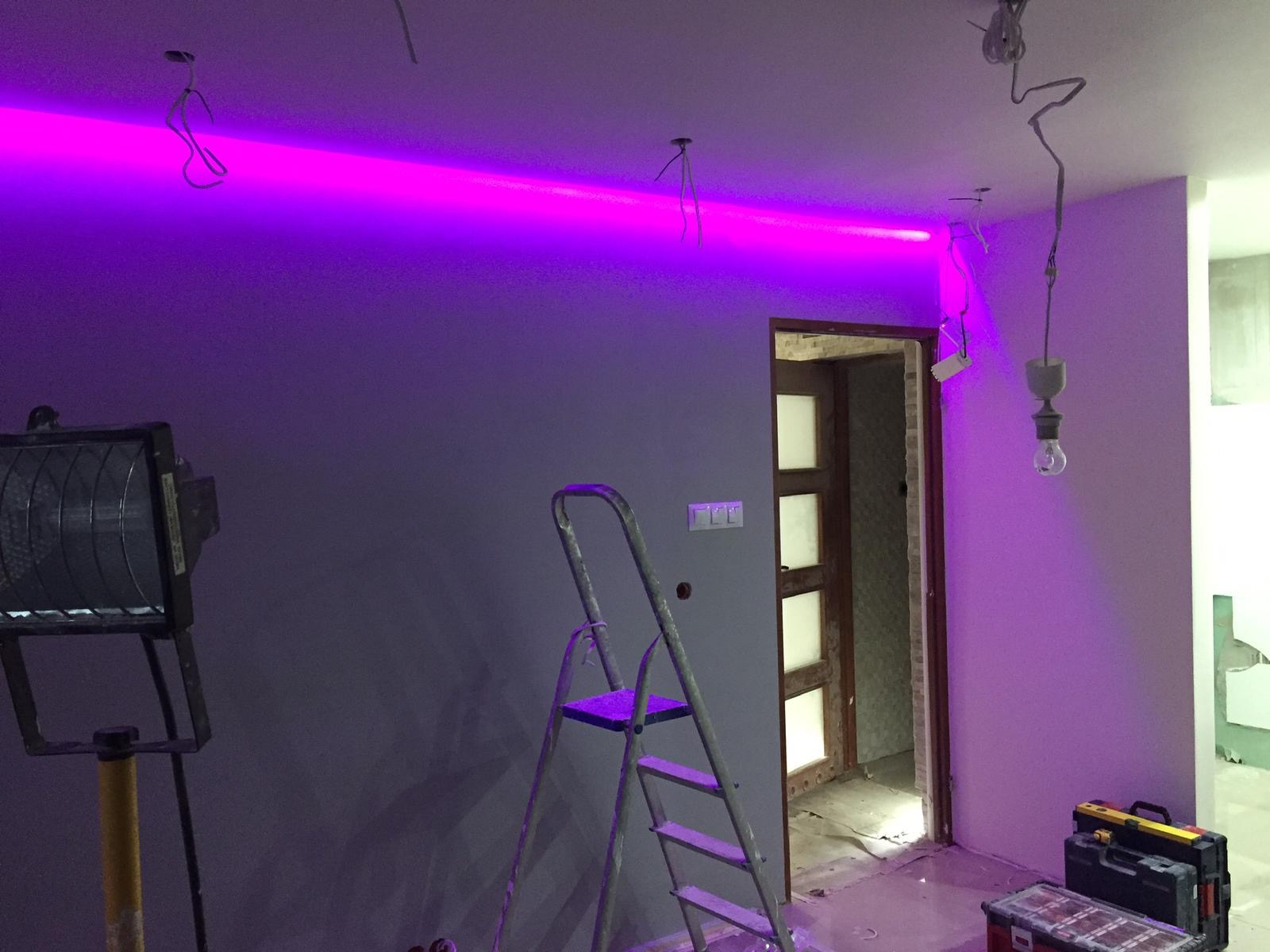 Częstochowa: Wnętrze w trakcie prac wykończeniowych, widoczne szare ściany, drabina, narzędzia, prowizoryczne oświetlenie i zamontowana listwa LED z fioletowym światłem, sugerująca etap...