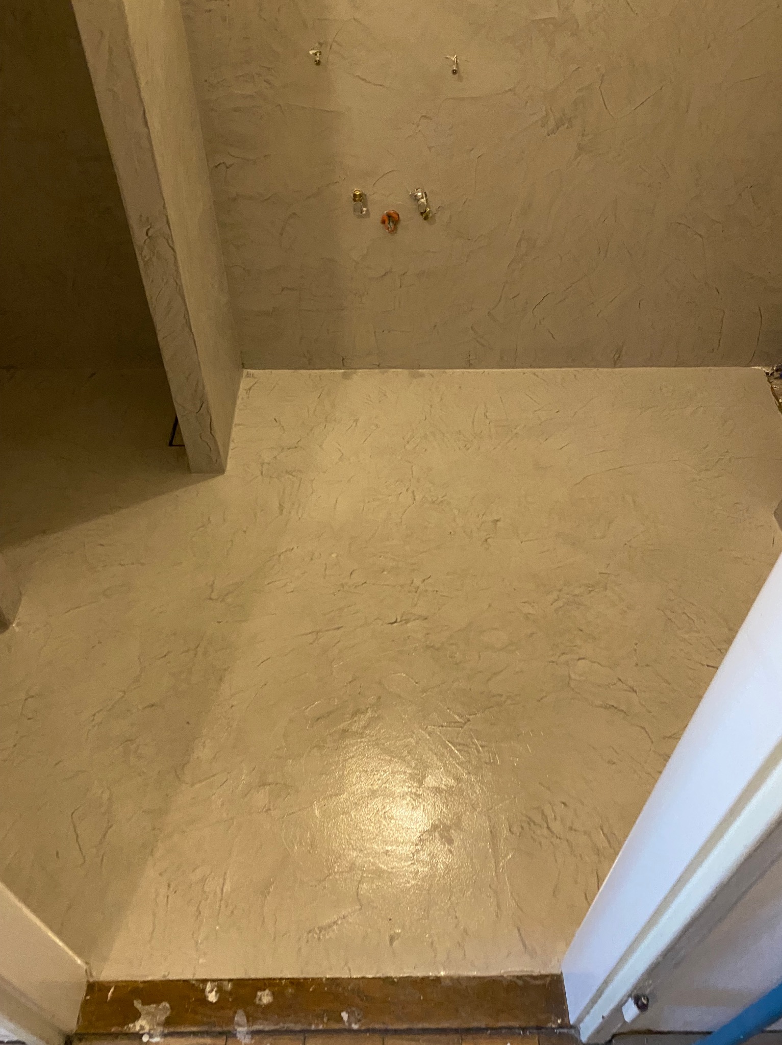 Wykończona łazienka w Bochni z dekoracyjną, beżową strukturą na ścianach i suficie. Widoczne wystające elementy instalacji.