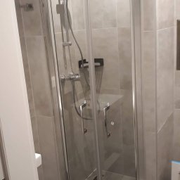 RENOVATION SYSTEMS Emil Oporski - Nowoczesna kabina prysznicowa z szarymi płytkami, chromowaną armaturą i szklanymi drzwiami, widok z boku.
