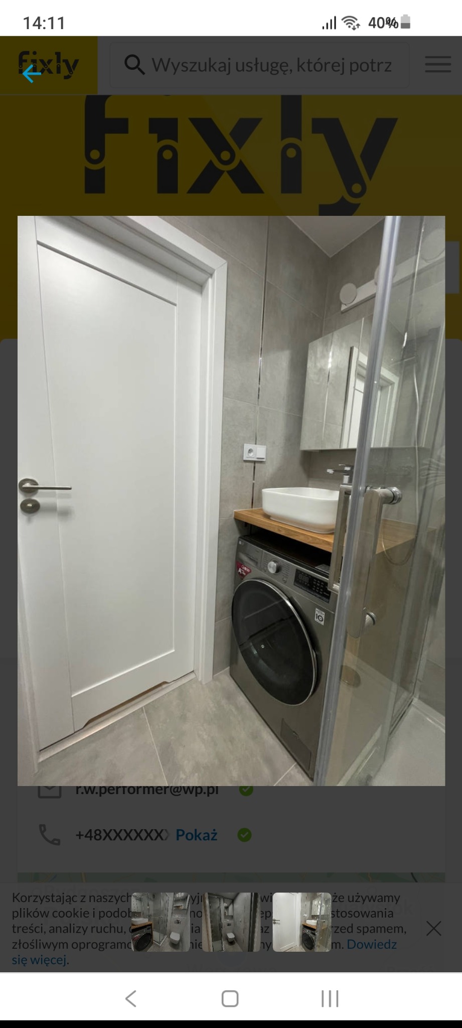 Nowoczesna łazienka z szarymi płytkami, białą umywalką na drewnianym blacie, pralką LG i przeszkloną kabiną prysznicową.