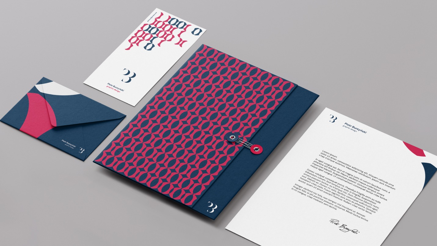 Komplet materiałów firmowych w kolorach granatowym i różowym, zawierający papier firmowy, wizytówkę, kopertę i teczkę z zapięciem na sznurek, ułożone na szarym tle pod kątem.