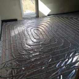 Instalacja ogrzewania podłogowego w trakcie montażu w Biskupcu, rury ułożone na folii z siatką, widok na okno i surowe ściany.