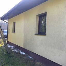 Minor Malowanie Dachów Natalia Szymczak - Fragment elewacji budynku z widoczną różnicą w kolorze po umyciu, drabina oparta o ścianę, na trawniku rozłożone węże i myjka ciśnieniowa.