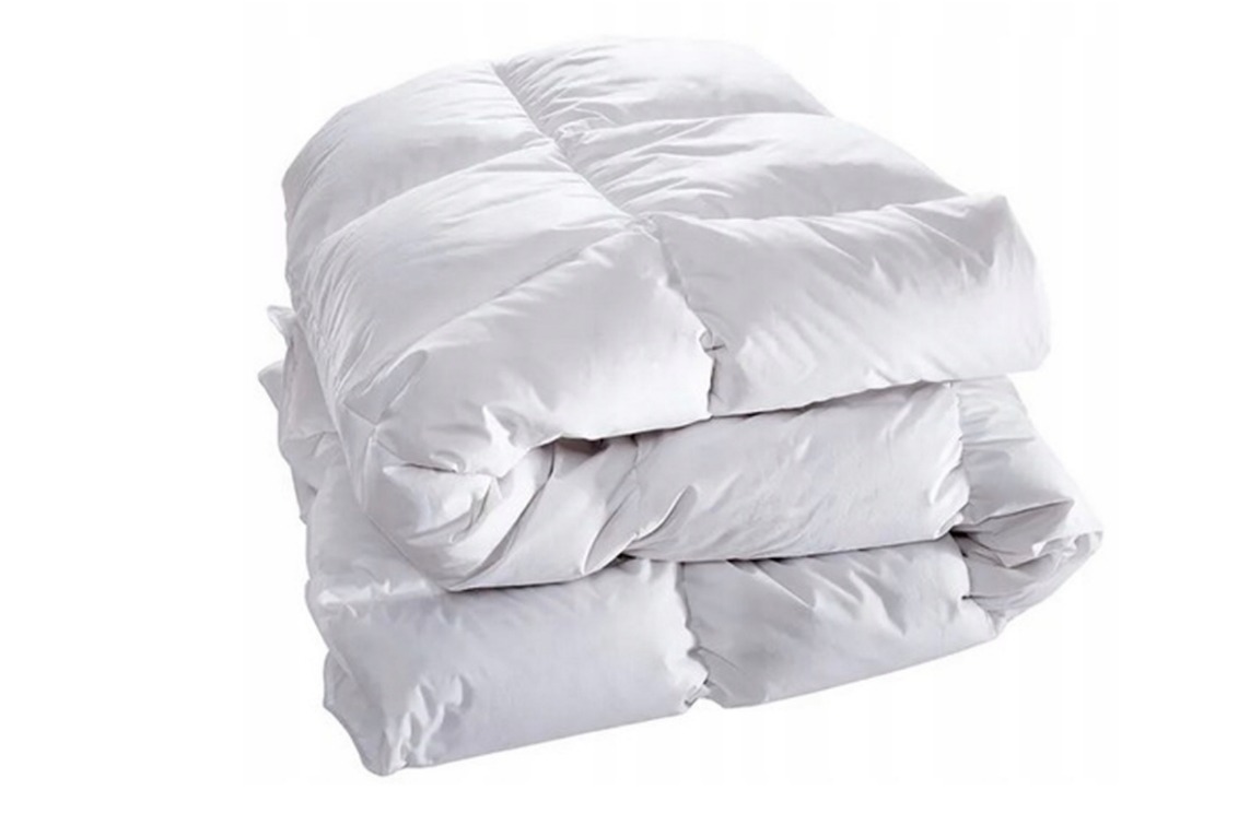 Stos białych, pikowanych kołder puchowych, widoczne symetryczne przeszycia tworzące kwadratowe panele, izolowane na białym tle.