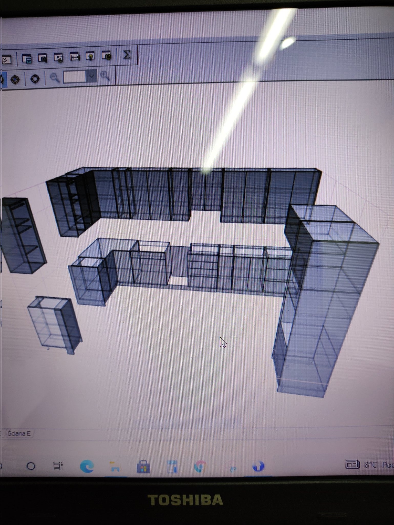 Prezentacja 3D projektu zabudowy meblowej na ekranie laptopa Toshiba, widoczne ikony programu projektowego i kursor myszy.