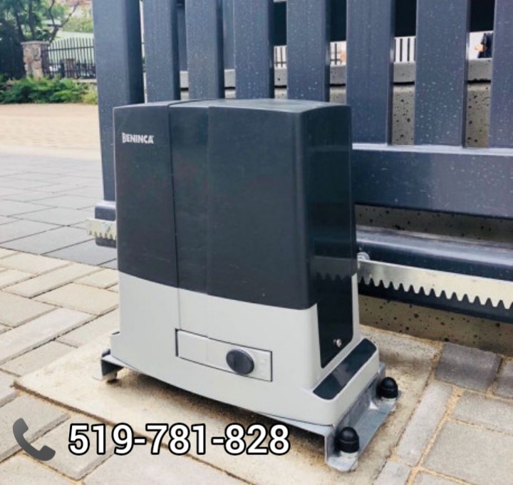 Szaro-czarny napęd do bram marki Beninca zamontowany na kostce brukowej, widoczna zębatka i fragment bramy.