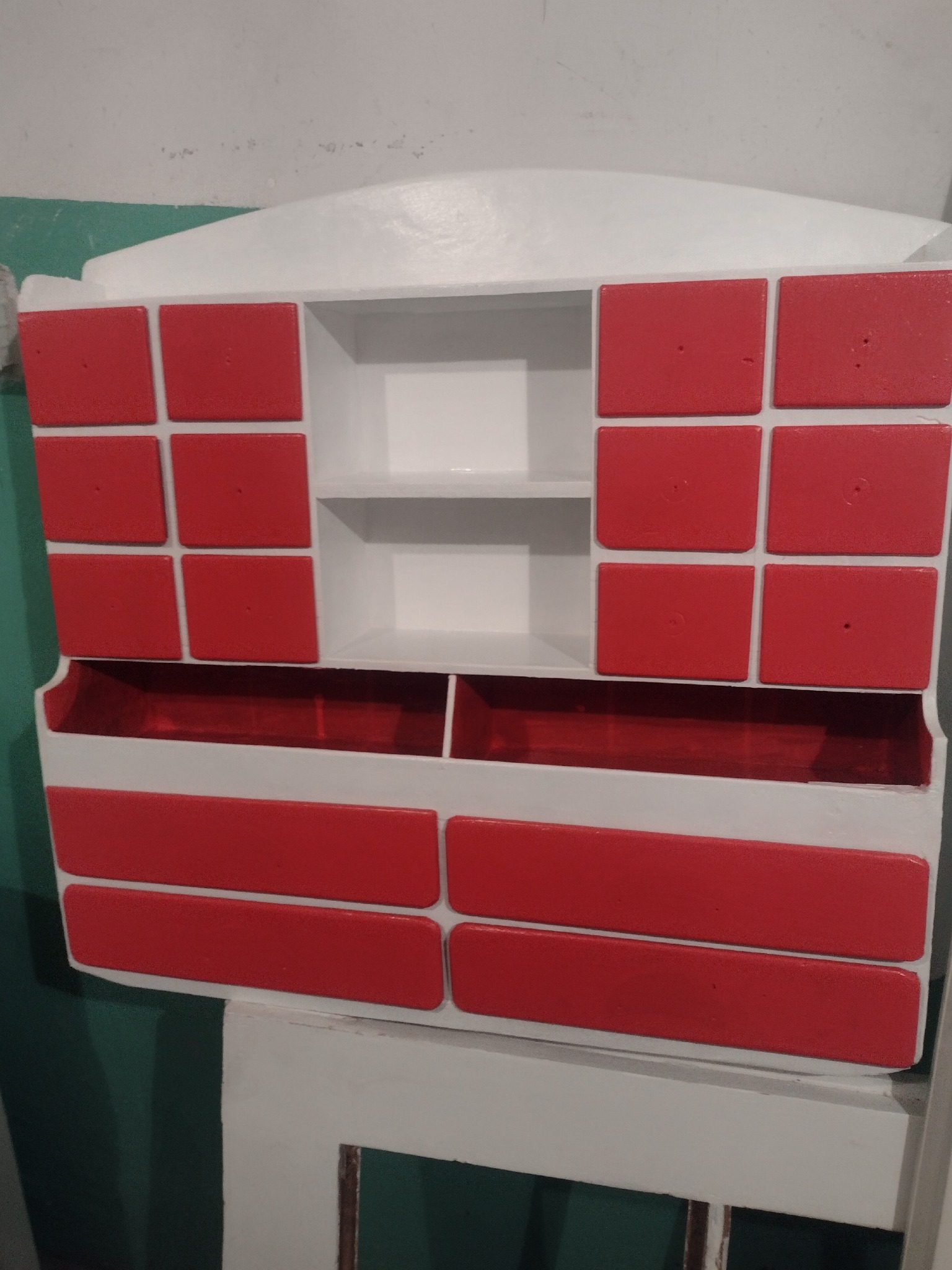 Odnowiona szafka z czerwonymi i białymi elementami, widoczne niedoskonałości malowania.