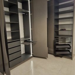 Rmeble RADOSŁAW PANUŚ - Nowoczesna szafa wnękowa z szarymi frontami, oświetleniem LED i wysuwanymi półkami na buty, ustawiona na jasnej, marmurkowej podłodze.