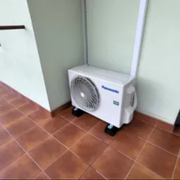 Agregat klimatyzacji Panasonic UZ zamontowany na balkonie, widoczne rury prowadzone w korytku i owinięte taśmą UV, urządzenie stoi na podkładkach antywibracyjnych.