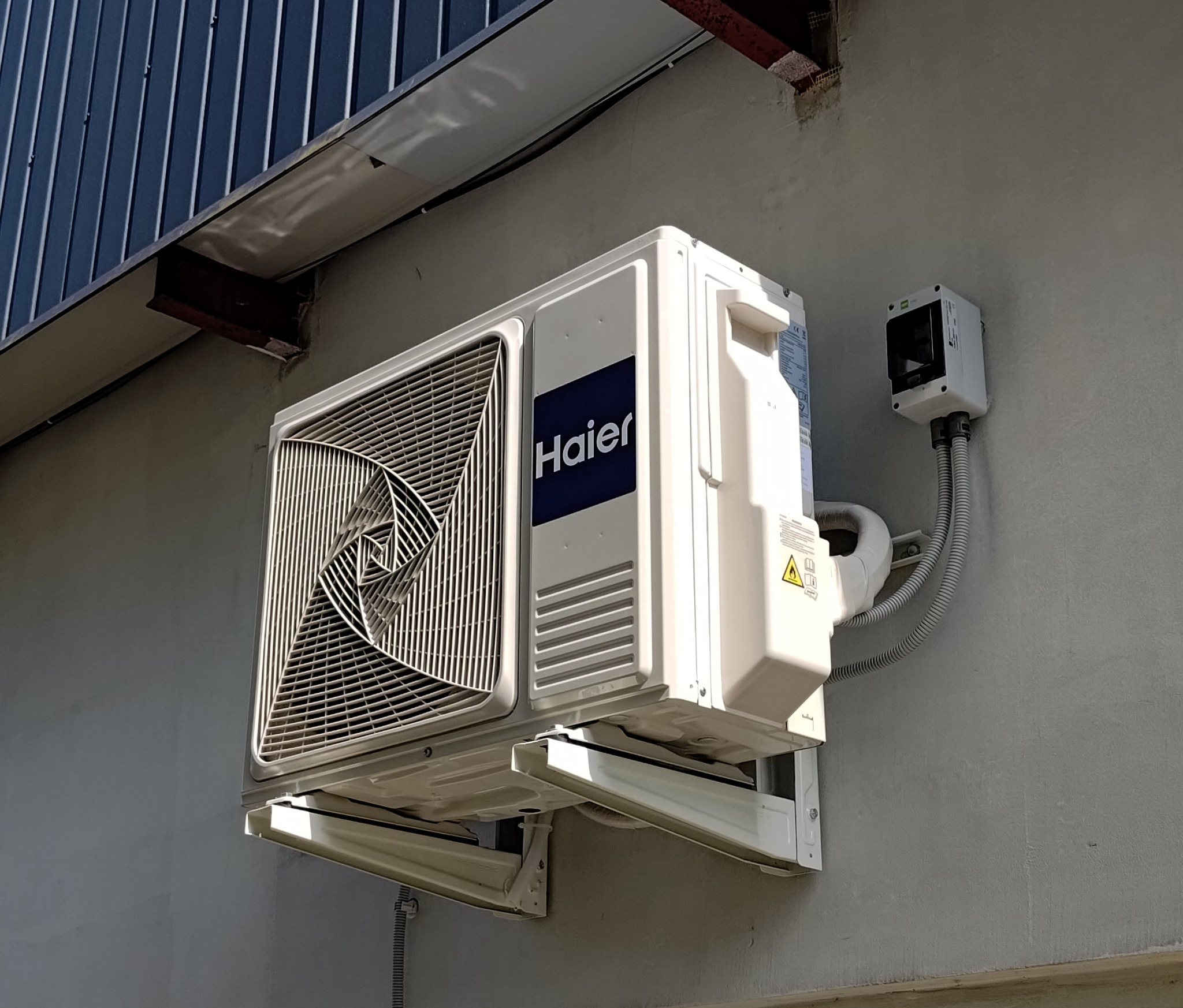 Jednostka zewnętrza klimatyzatora Haier Revive Plus zamocowanaa na podstawach na tyle kwiaciarni.