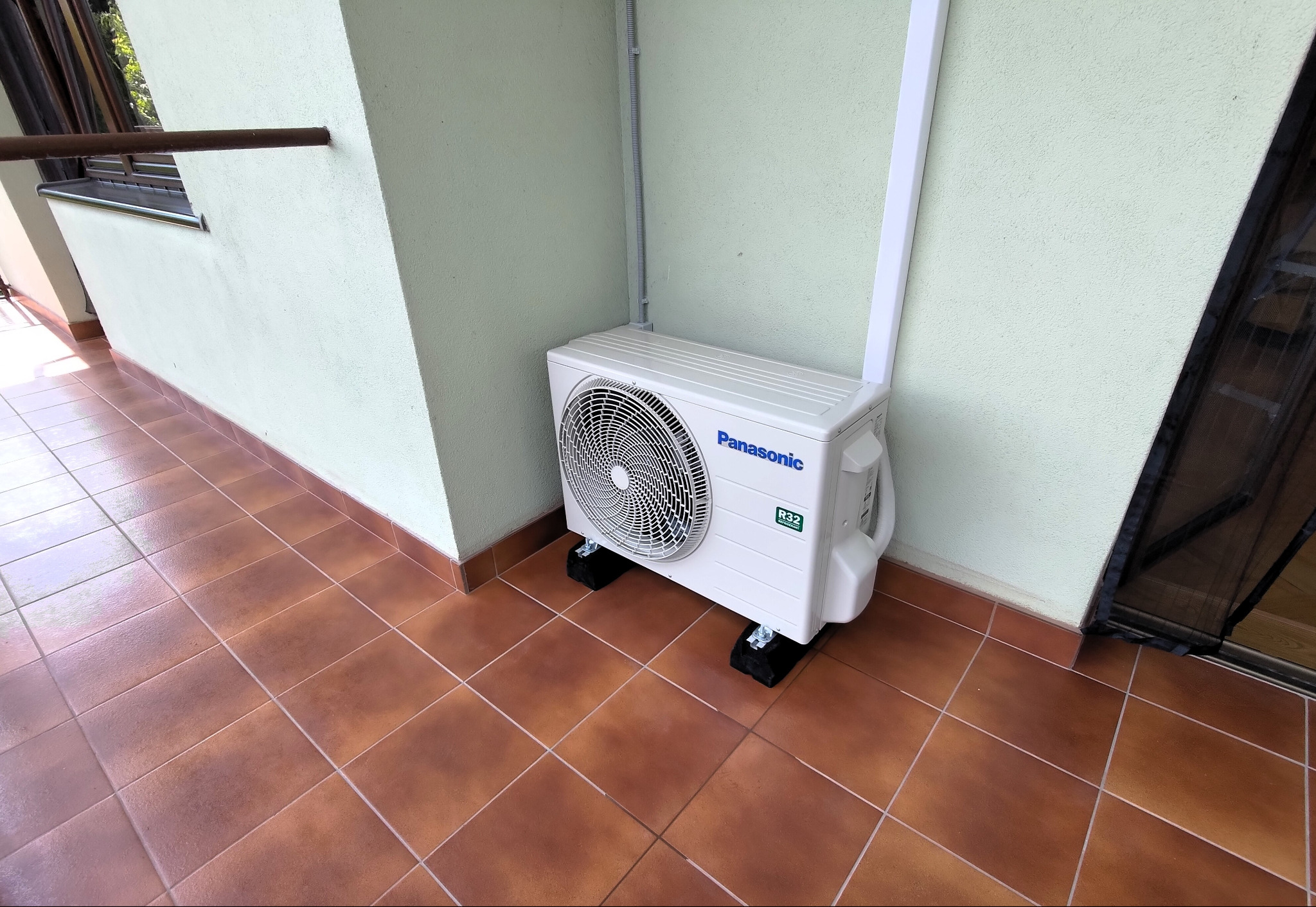 Agregat klimatyzacji Panasonic UZ zamontowany na balkonie, widoczne rury prowadzone w korytku i owinięte taśmą UV, urządzenie stoi na podkładkach antywibracyjnych.