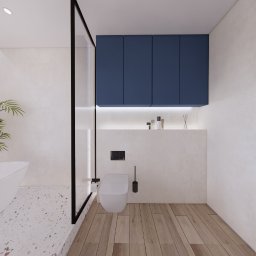 PPKstudio - Nowoczesna łazienka z wiszącą toaletą, zabudową meblową w kolorze granatowym, drewnianą podłogą i fragmentem wanny na tle mozaiki.
