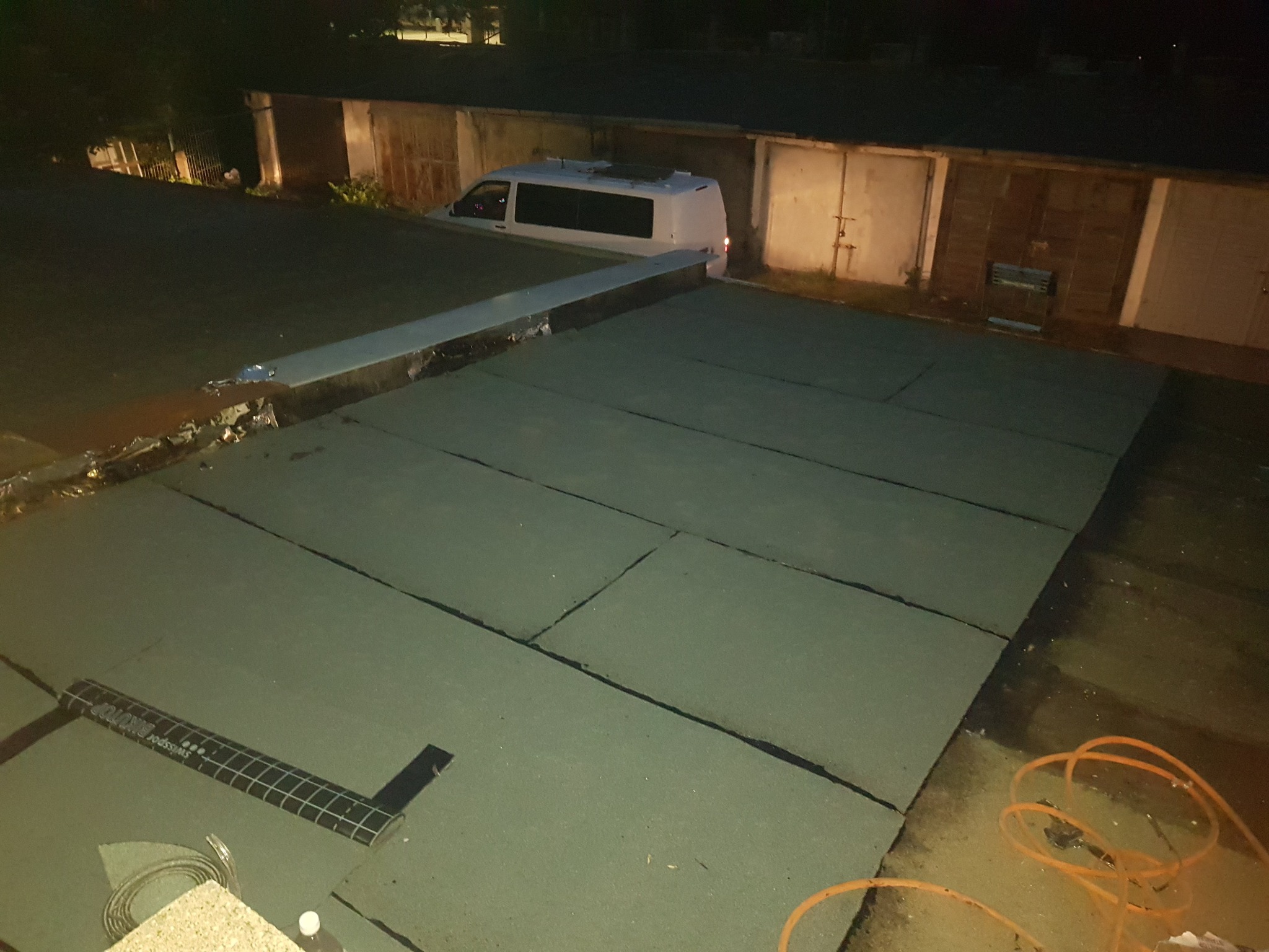 Montaż izolacji termicznej na płaskim dachu, widoczny biały van w tle, narzędzie pomiarowe Swissport Binutop