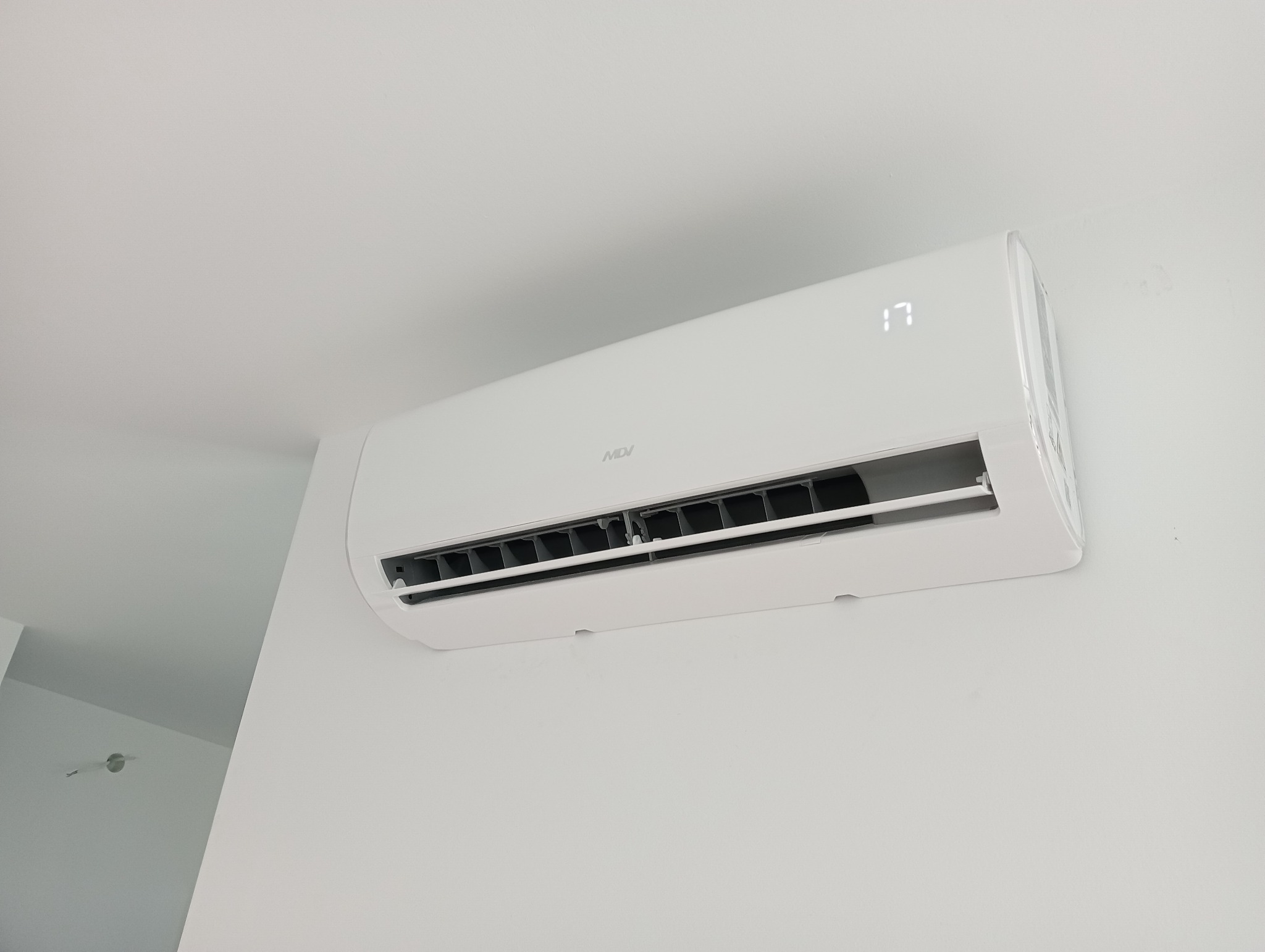 Biały klimatyzator MDV zamontowany na białej ścianie, wyświetlający temperaturę 17 stopni Celsjusza.