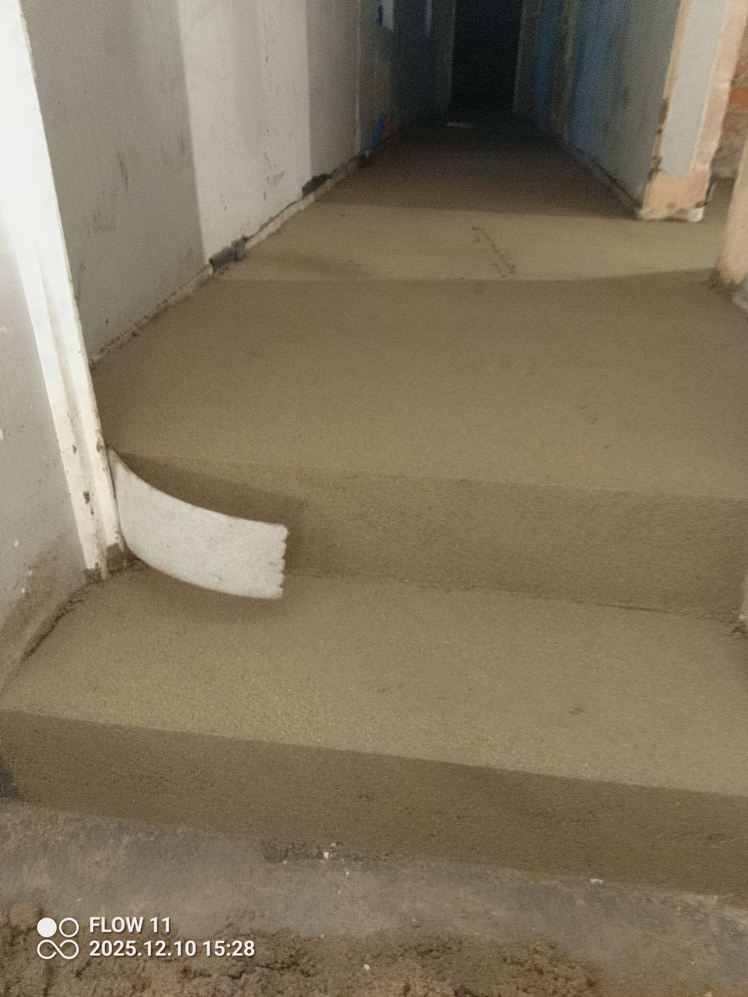 Wyrównana, świeża posadzka jastrychowa w korytarzu, z widoczną listwą przypodłogową i surowymi ścianami. Ujęcie z dołu, podkreślające gładką powierzchnię.