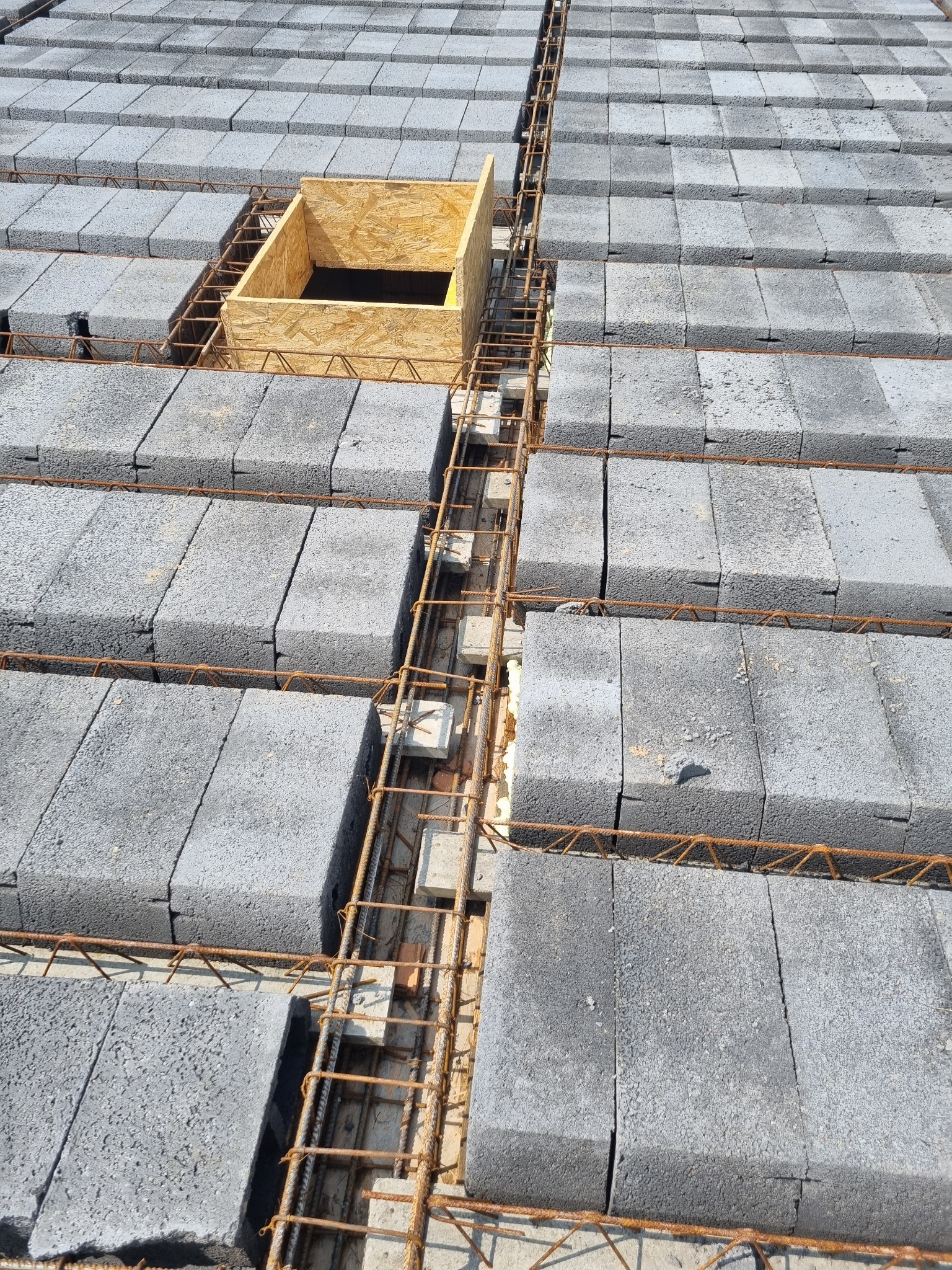 Budowa stropu Teriva z widoczną szalunką otworu i zbrojeniem w trakcie montażu, widok z góry.