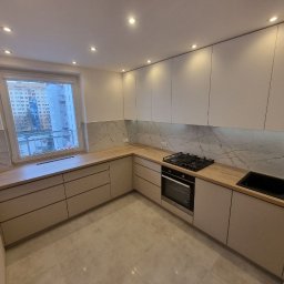 Vasyl Smachynskyi - Nowoczesna kuchnia z jasnymi, gładkimi frontami szafek, drewnianym blatem i marmurowym panelem nad blatem, widok na miasto przez okno.