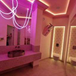 Vasyl Smachynskyi - Awangardowa łazienka w różu: lustro z neonowym akcentem, umywalka z terazzo, toaleta i dekoracja ścienna w kształcie flakonu perfum. Nietypowy design.
